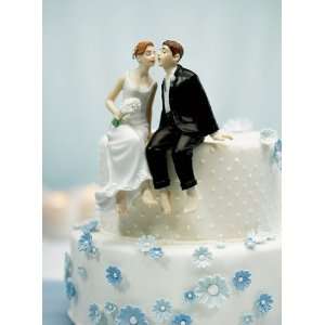 Whimsical Bride and Groom Sitting on Edge of the Cake  